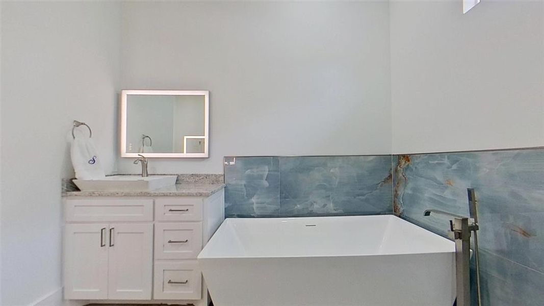 Freestanding soaking tub with a floor-mounted brushed nickel filler Freestanding soaking tub with a floor-mounted brushed nickel filler