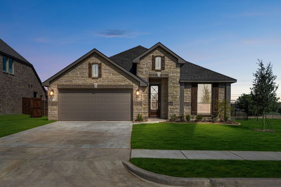 Single-story home with stone exterior, two-car garage, and manicured front lawn at dusk