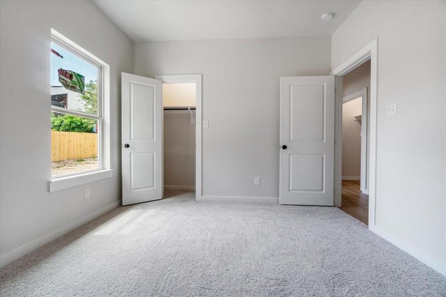 Unfurnished bedroom featuring a closet, light colored carpet, and a spacious closet