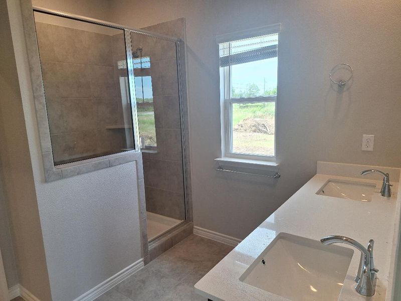 Full bathroom featuring a stall shower, tile patterned floors, and double vanity Full bathroom featuring a stall shower, tile patterned floors, and double vanity