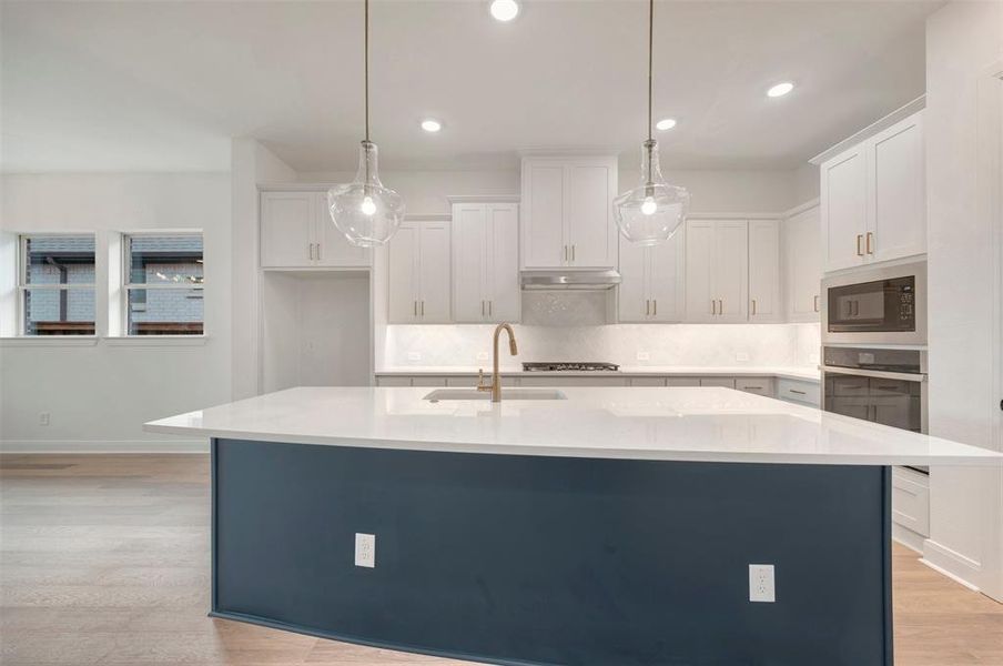 Modern kitchen featuring a large central island with a contrasting base, white countertops, and white cabinetry