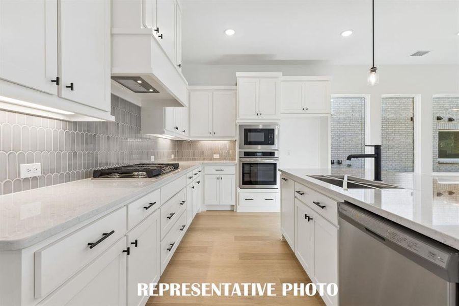 Beautiful cabinetry, gorgeous countertops and designer backsplash effortlessly pair with contemporary stainless steel to create a kitchen for the ages!  REPRESENTATIVE PHOTO