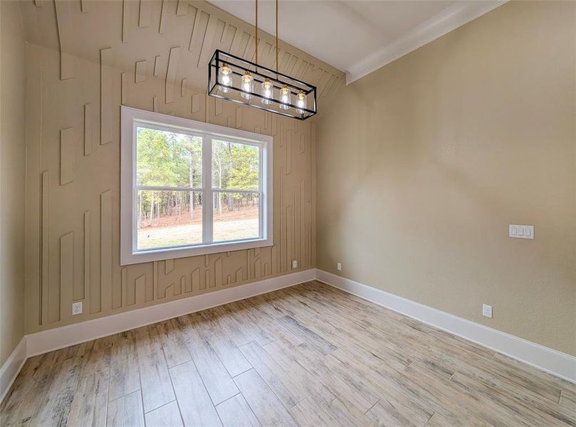 Unfurnished room featuring light wood-style floors, a chandelier, and crown molding