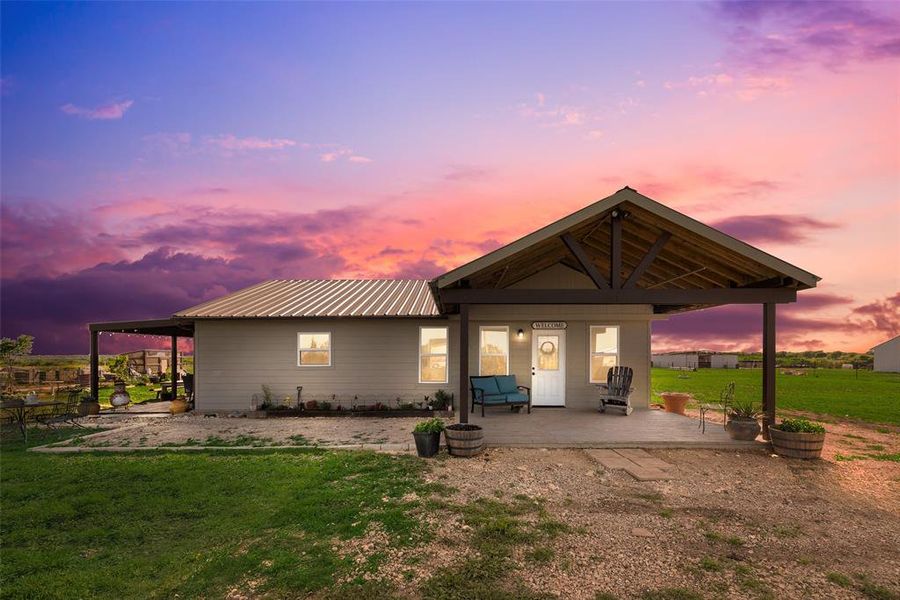 Back of property featuring a yard, metal roof, and a patio area