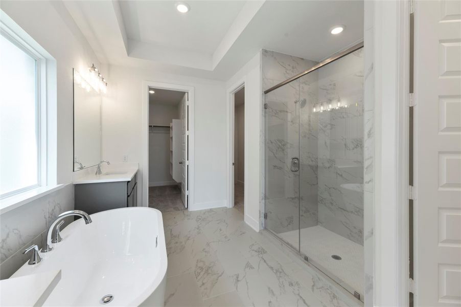 Bathroom featuring a marble finish shower, double vanity, a raised ceiling, recessed lighting, and a walk in closet Bathroom featuring a marble finish shower, double vanity, a raised ceiling, recessed lighting, and a walk in closet