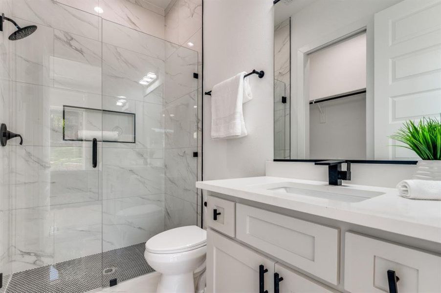 Bathroom with a marble finish shower, vanity, and a spacious closet Bathroom with a marble finish shower, vanity, and a spacious closet