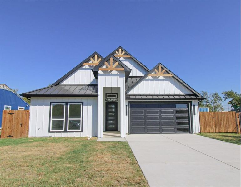 Modern inspired farmhouse with a standing seam roof, board and batten siding, a metal roof, concrete driveway, and a garage Modern inspired farmhouse with a standing seam roof, board and batten siding, a metal roof, concrete driveway, and a garage