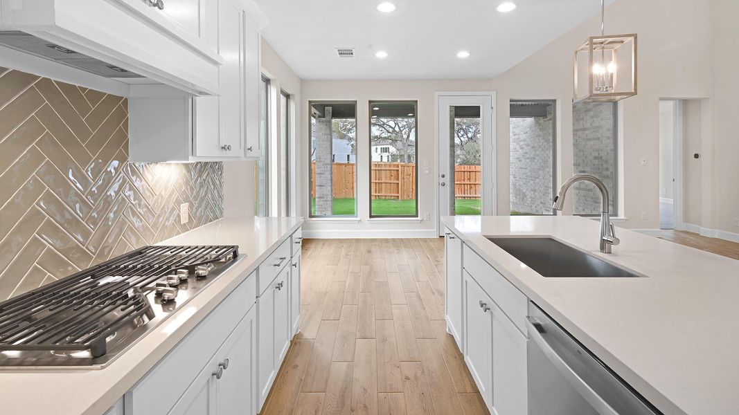 Kitchen featuring hanging light fixtures, white cabinets, light wood finished floors, exhaust hood, and recessed lighting