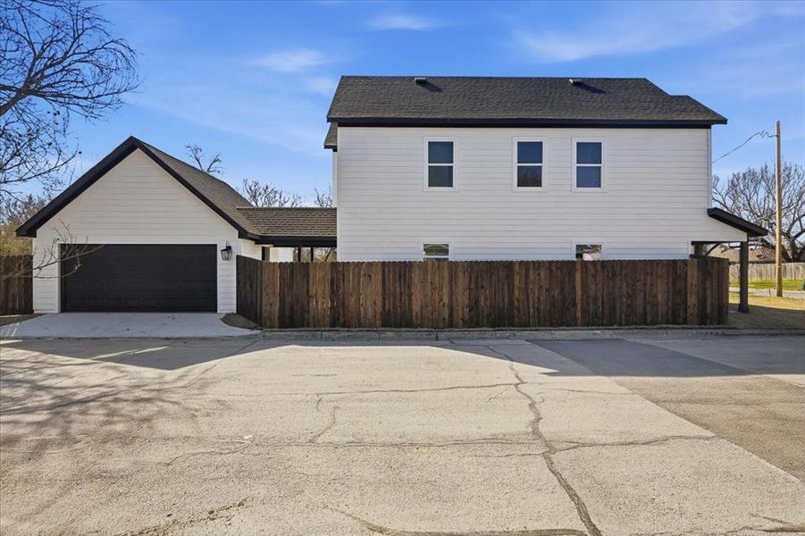 View of home's exterior with roof with shingles, concrete driveway, and an attached garage