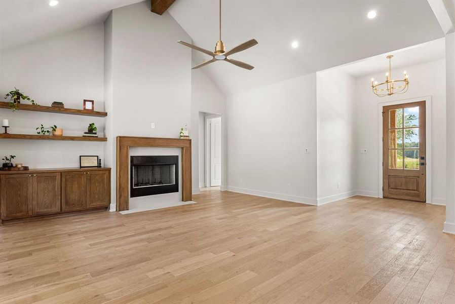 Unfurnished living room featuring recessed lighting, light wood finished floors, ceiling fan, a fireplace with flush hearth, and high vaulted ceiling