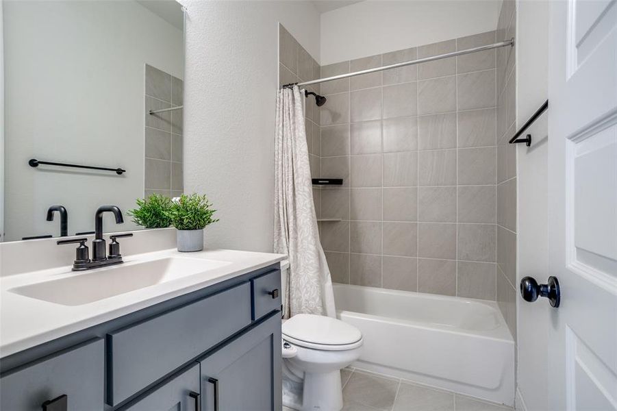 Full bath featuring vanity, shower / bath combo with shower curtain, and light tile patterned floors
