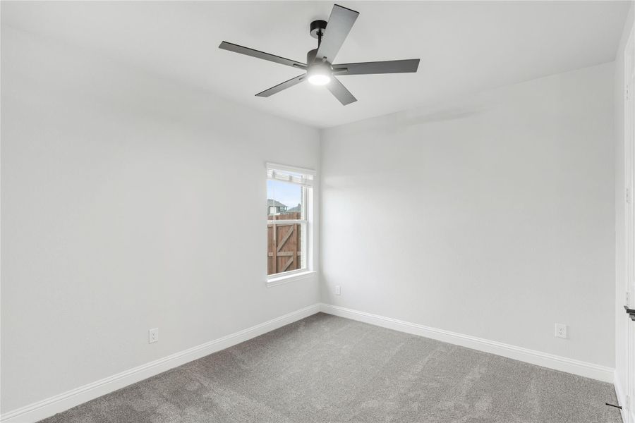 Empty bedroom with gray carpet, ceiling fan, and single window with white walls
