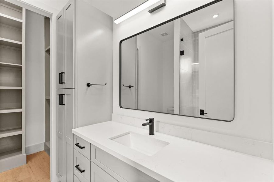 Additional secondary bathroom features walk-in closet, modern lighting, extended quartz countertop and plenty of storage below.