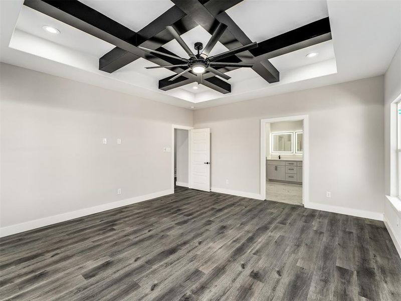 Unfurnished bedroom featuring coffered ceiling, beam ceiling, dark wood-type flooring, and ensuite bath