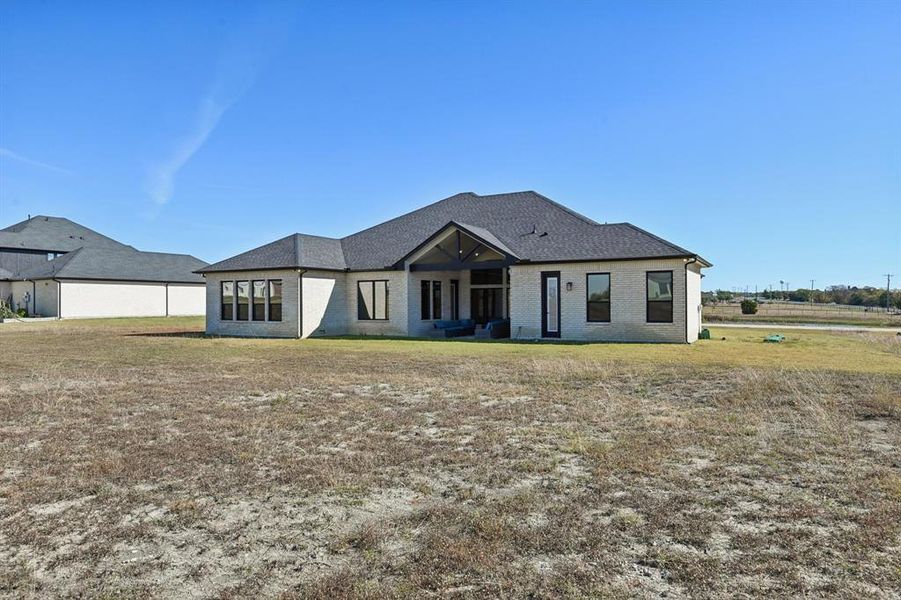 Rear view of house featuring brick siding, a patio area, and a lawn Rear view of house featuring brick siding, a patio area, and a lawn