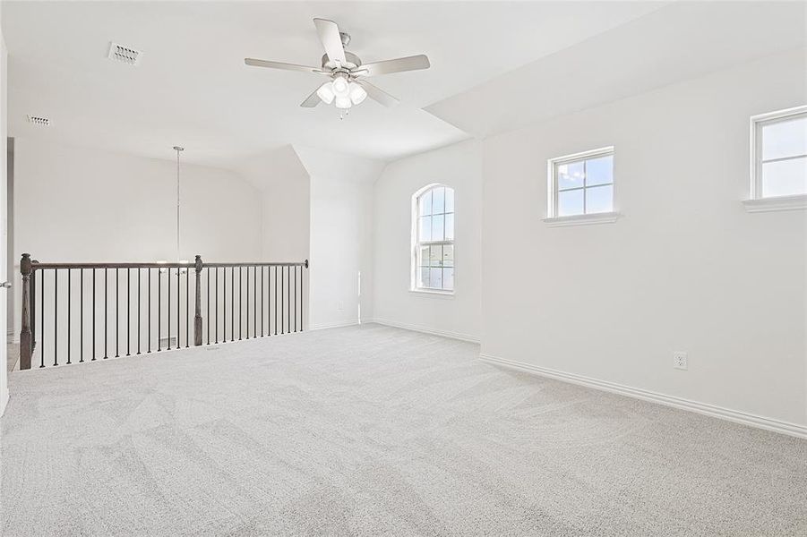 Unfurnished room featuring ceiling fan, carpet flooring, and lofted ceiling Unfurnished room featuring ceiling fan, carpet flooring, and lofted ceiling