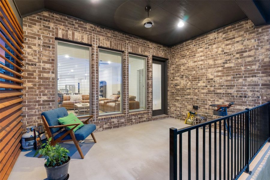Outdoor covered patio featuring a brick exterior wall and concrete flooring