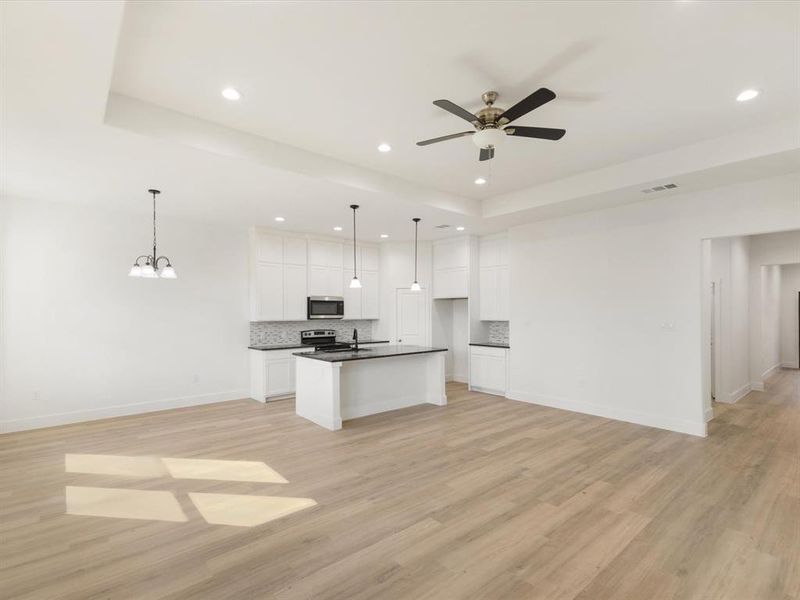 Kitchen with open floor plan, dark countertops, white cabinets, decorative backsplash, and recessed lighting