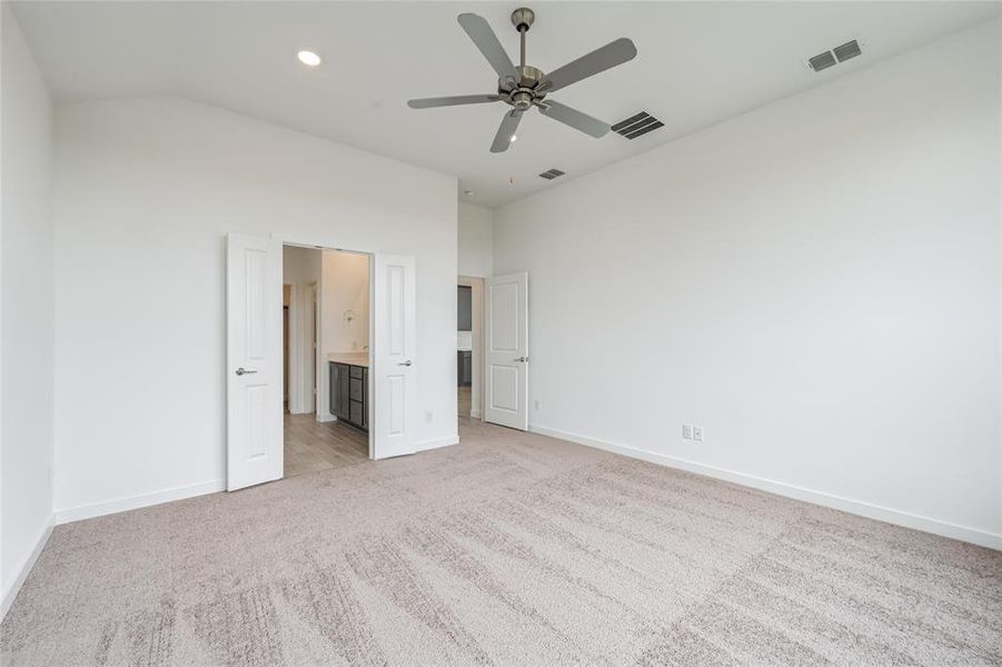 Unfurnished bedroom with ceiling fan, light colored carpet, and ensuite bathroom