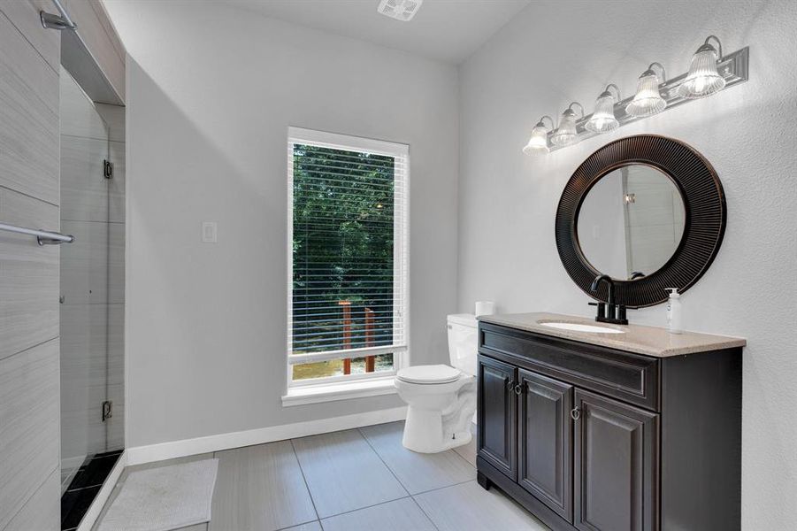 Bathroom featuring toilet, vanity, a shower stall, and tile patterned floors