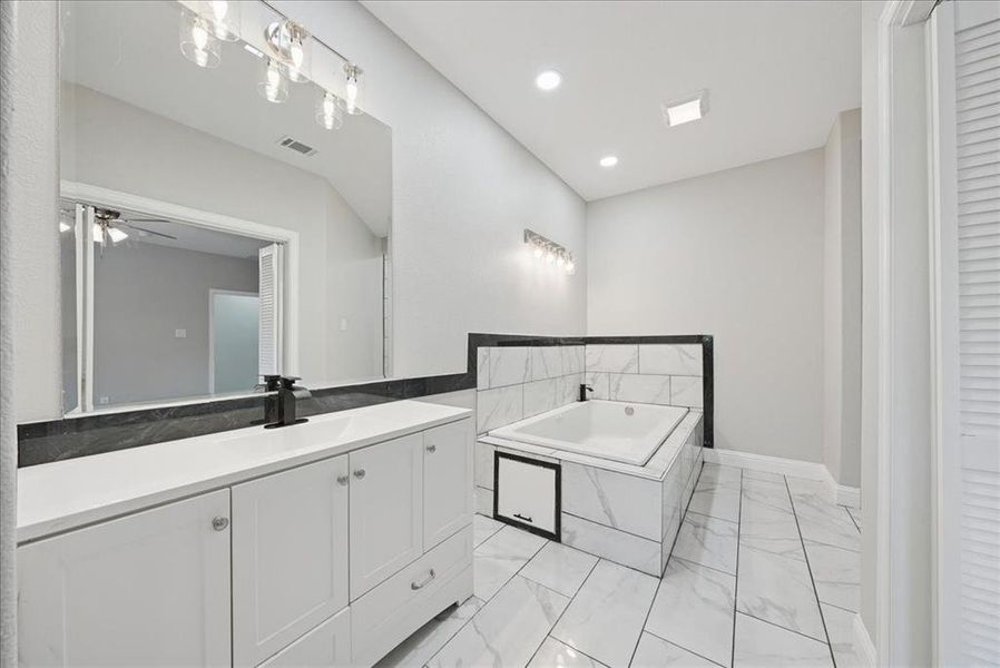 Full bath featuring vanity, a garden tub, light marble finish floors, ceiling fan, and recessed lighting