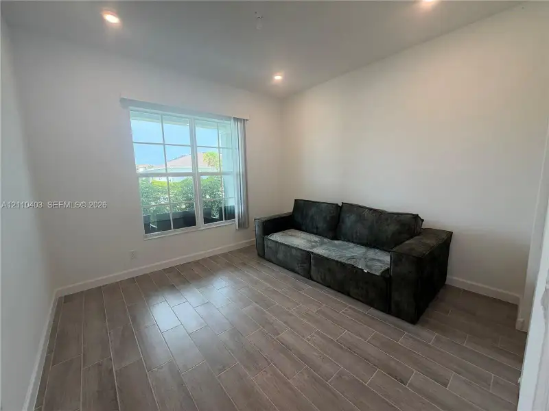 Neutral-toned room featuring wood-finish tile flooring, recessed ceiling lighting, and a multi-pane window