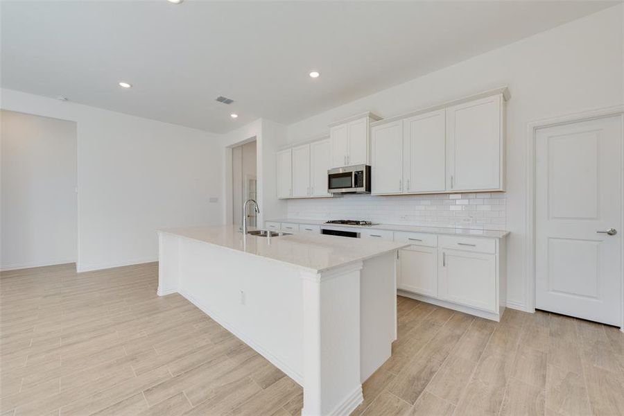 Kitchen featuring white cabinetry and a center island with sink