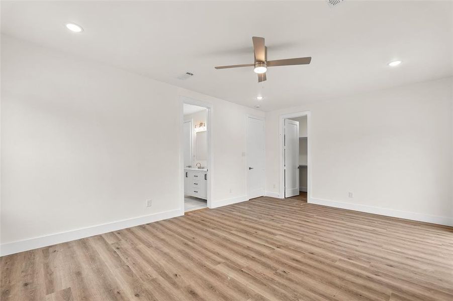 Unfurnished bedroom featuring a spacious closet, recessed lighting, a ceiling fan, light wood-type flooring, and connected bathroom Unfurnished bedroom featuring a spacious closet, recessed lighting, a ceiling fan, light wood-type flooring, and connected bathroom