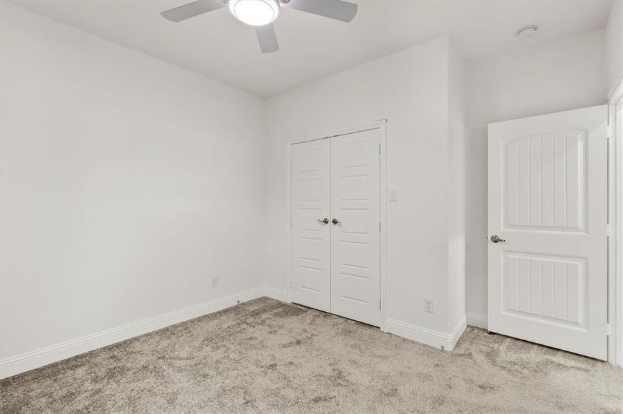 Unfurnished bedroom with a closet, ceiling fan, and light carpet