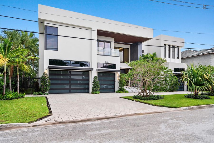 Striking modern exterior with clean architectural lines, sleek glass garage doors, and lush tropical landscaping. Striking modern exterior with clean architectural lines, sleek glass garage doors, and lush tropical landscaping.