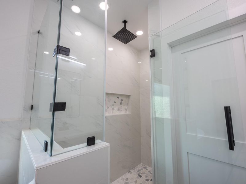 Step into this elegant walk-in shower featuring full-height tile surround, a niche for essentials, and a matte black rain showerhead for that spa-day feel at home. Step into this elegant walk-in shower featuring full-height tile surround, a niche for essentials, and a matte black rain showerhead for that spa-day feel at home.