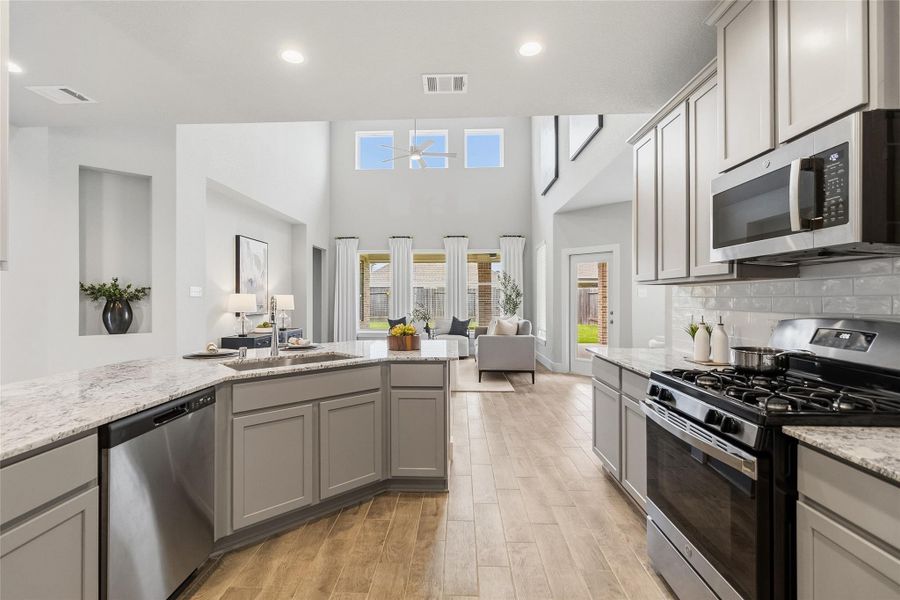 Your beautifully appointed kitchen flows seamlessly into the soaring two-story living area, showcasing granite countertops, stainless steel appliances, abundant cabinetry, and an ideal layout for entertaining and daily living.