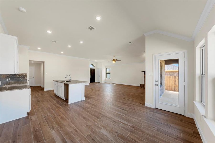 Kitchen with arched walkways, white cabinets, ornamental molding, dark stone countertops, and open floor plan