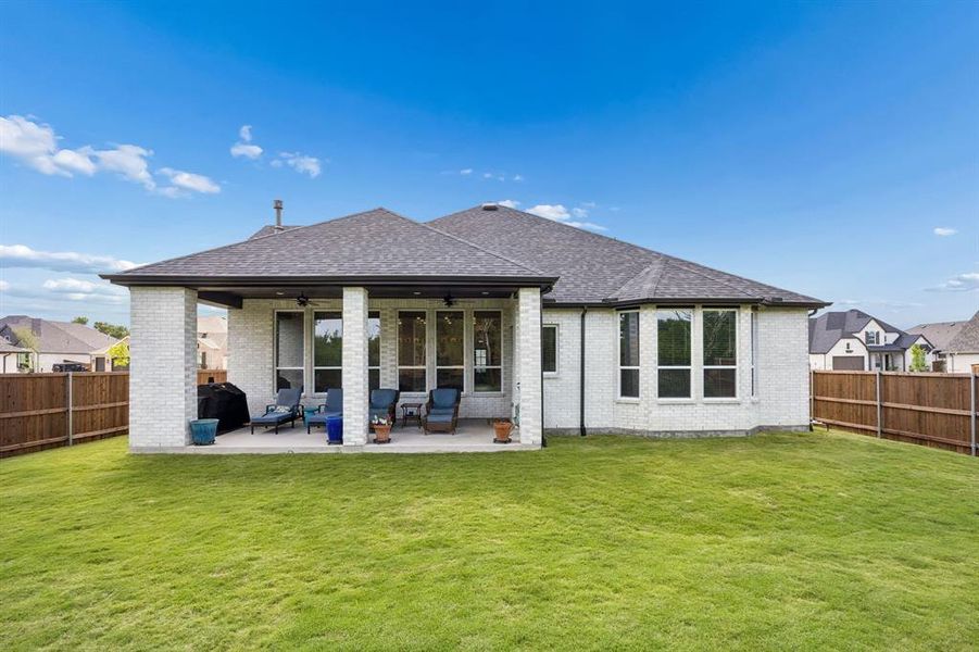 Expansive backyard featuring a covered patio, brick exterior, large windows, and a privacy fence Expansive backyard featuring a covered patio, brick exterior, large windows, and a privacy fence