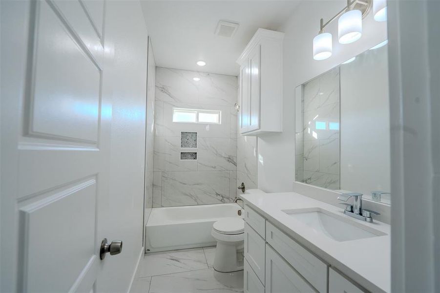 Full bathroom featuring light marble finish floors, vanity, and a combined bath / shower with marble appearance Full bathroom featuring light marble finish floors, vanity, and a combined bath / shower with marble appearance