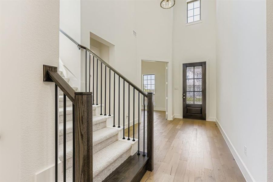 Entryway with light wood-type flooring, stairs, and a high ceiling Entryway with light wood-type flooring, stairs, and a high ceiling