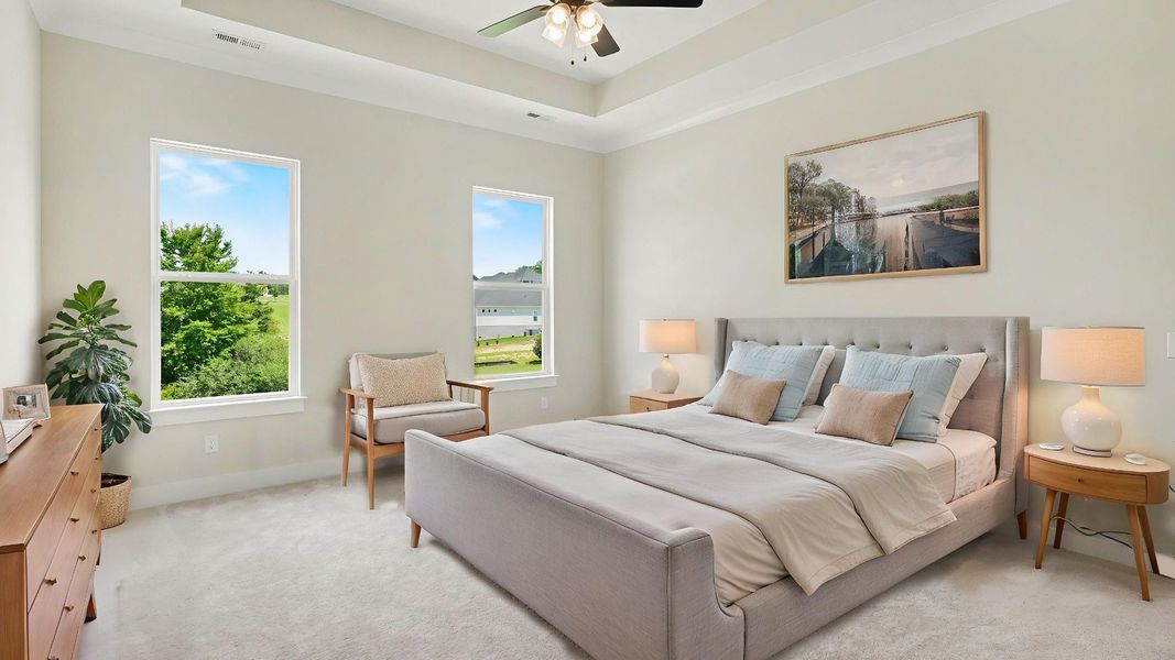 Primary suite with tray ceiling, ceiling fan, and carpet Primary suite with tray ceiling, ceiling fan, and carpet