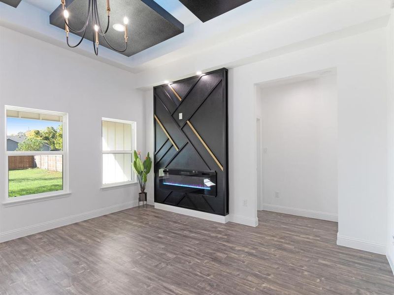 Spare room with dark wood-type flooring, a raised ceiling, and a chandelier