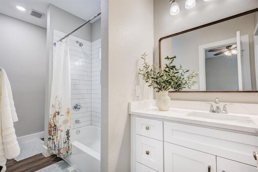 Bathroom with vanity, hardwood / wood-style flooring, shower / tub combo, and ceiling fan