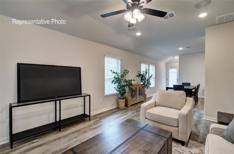 Living room with ceiling fan, lofted ceiling, and hardwood / wood-style flooring