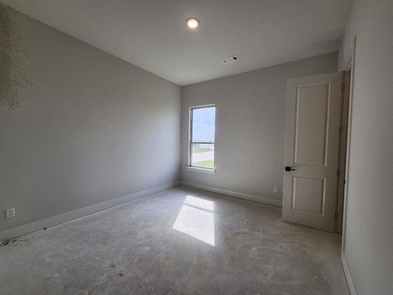 Bright interior space featuring a single window, white paneled door with black hardware, and an overhead flush-mount light fixture