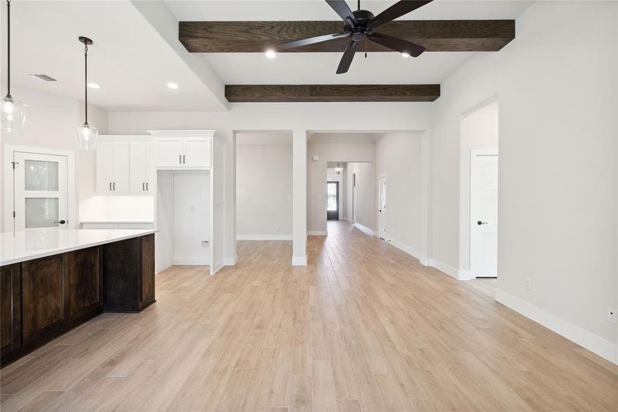 Kitchen featuring hanging light fixtures, ceiling fan, light wood-type flooring, beamed ceiling, and white cabinetry