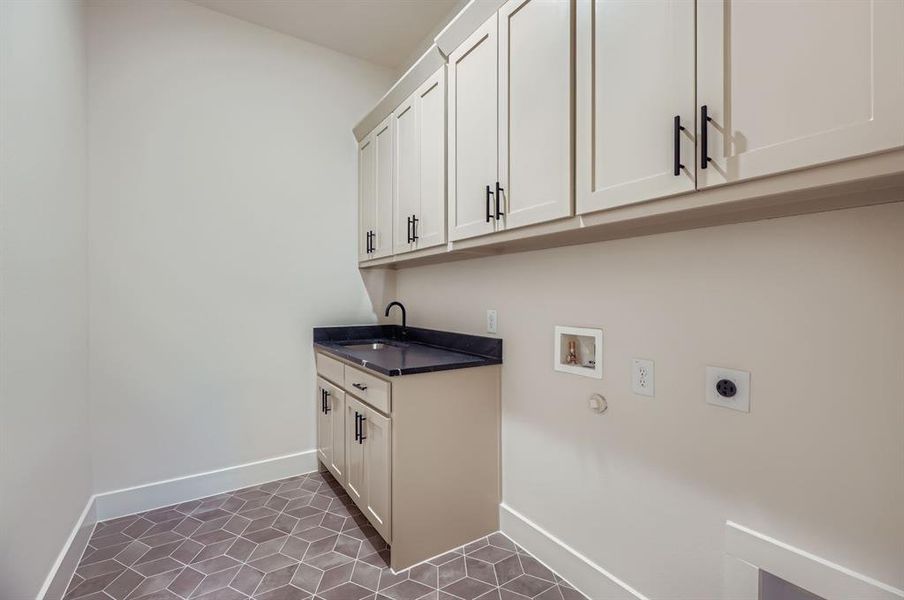 Laundry area featuring electric dryer hookup, cabinet space, hookup for a washing machine, and dark tile patterned flooring