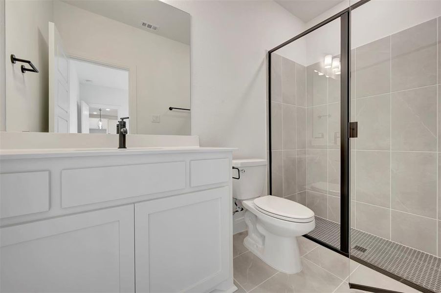 Full bath featuring vanity, a stall shower, and light tile patterned floors