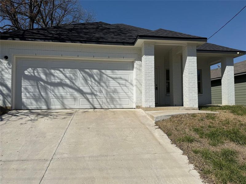 View of front of house with a garage, concrete driveway, brick siding, and roof with shingles