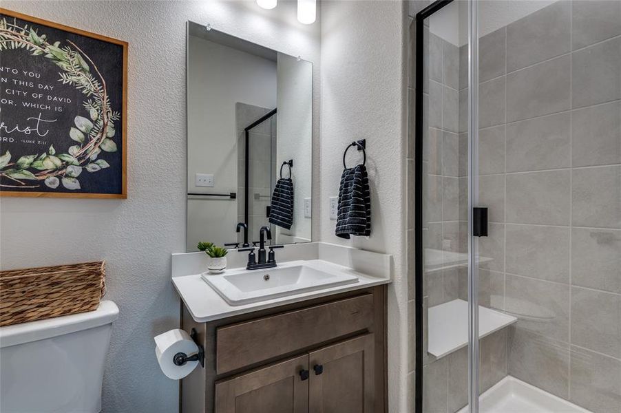 Bathroom featuring a textured wall, a shower stall, and vanity