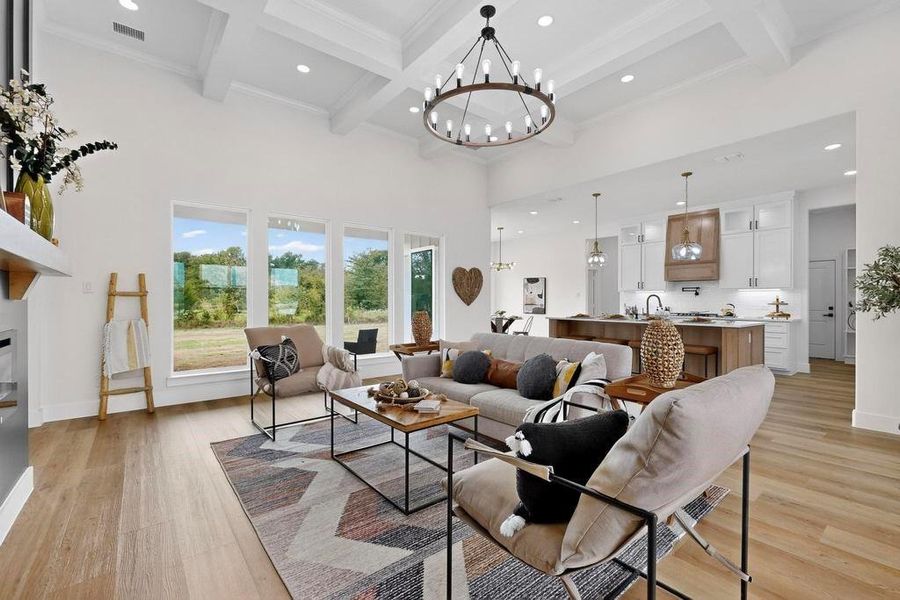 Living room featuring beamed ceiling, recessed lighting, a chandelier, a high ceiling, and a glass covered fireplace Living room featuring beamed ceiling, recessed lighting, a chandelier, a high ceiling, and a glass covered fireplace