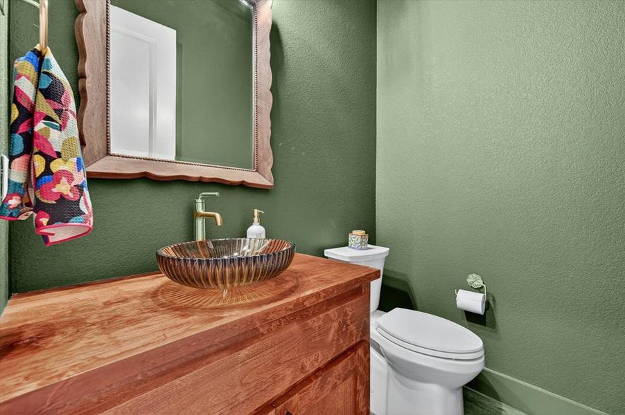 Custom wood-finish vanity featuring a glass vessel sink and a brass-finish faucet
