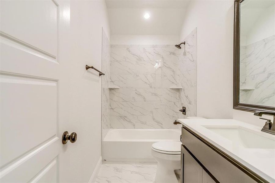 Full bathroom featuring tiled shower / bath, vanity, and toilet