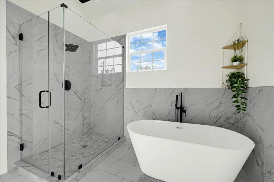 Luxurious en suite bathroom featuring a sleek glass shower and elegant freestanding tub, perfect for relaxation.